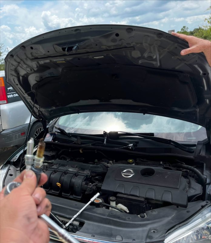 Engine work in progress, holding a spark plug beside the engine